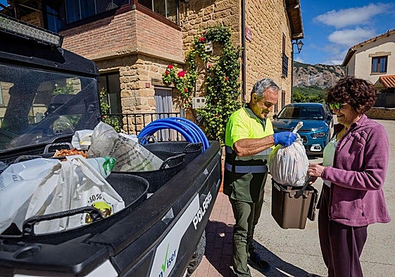 Una vecina de Kripan entrega sus desperdicios a un empleado.