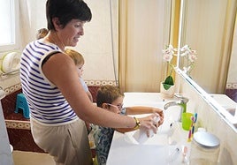 Una vecina lava las manos de sus hijos en la zona.
