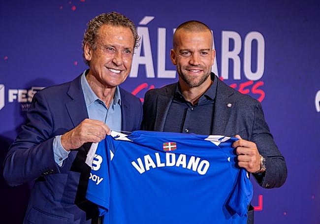 Jorge Valdano muestra la camiseta del Alavés que le ha entregado Víctor Laguardia.