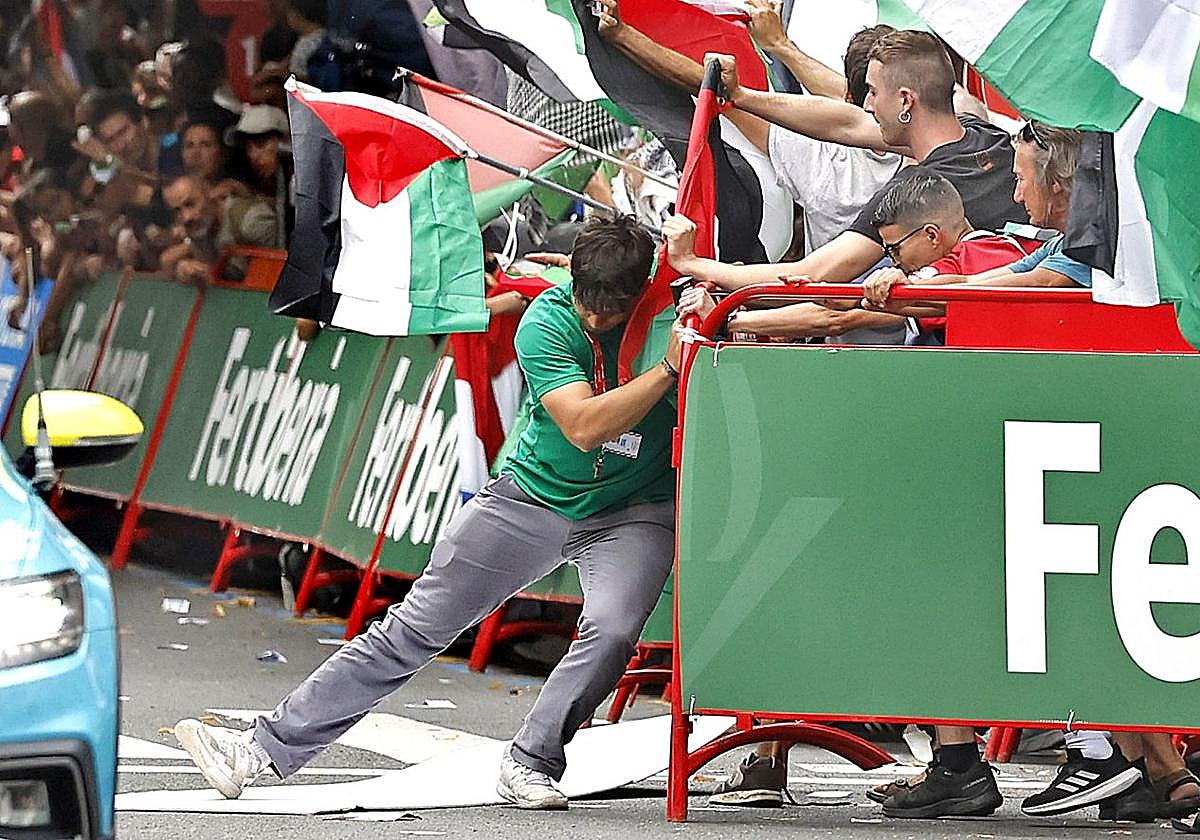 Un miembro de la organización trata de contener a los manifestantes antes de que se cancelase el final de la Vuelta en Bilbao este miércoles.