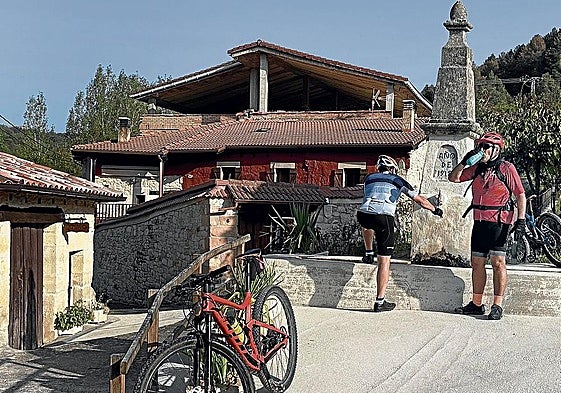 Dos ciclistas recuperan energías en la fuente de Cogullos.