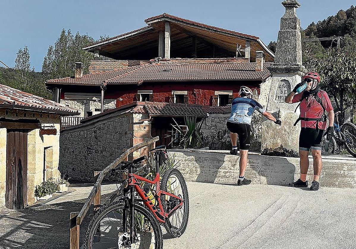 Dos ciclistas recuperan energías en la fuente de Cogullos.
