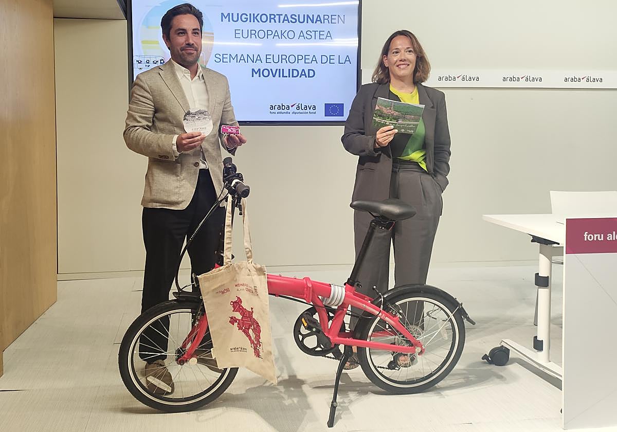 Jon Nogales, diputado de Movilidad Sostenible y Patricia Pérez, directora de Movilidad y Transportes posan junto a la bicicleta plegable, valorada en 500 euros, que recibirá la alavesa que más uso el transporte público el año pasado