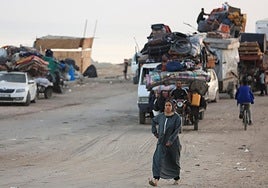 Una mujer camina mientras palestinos desplazados huyen del norte de Gaza hacia el sur.
