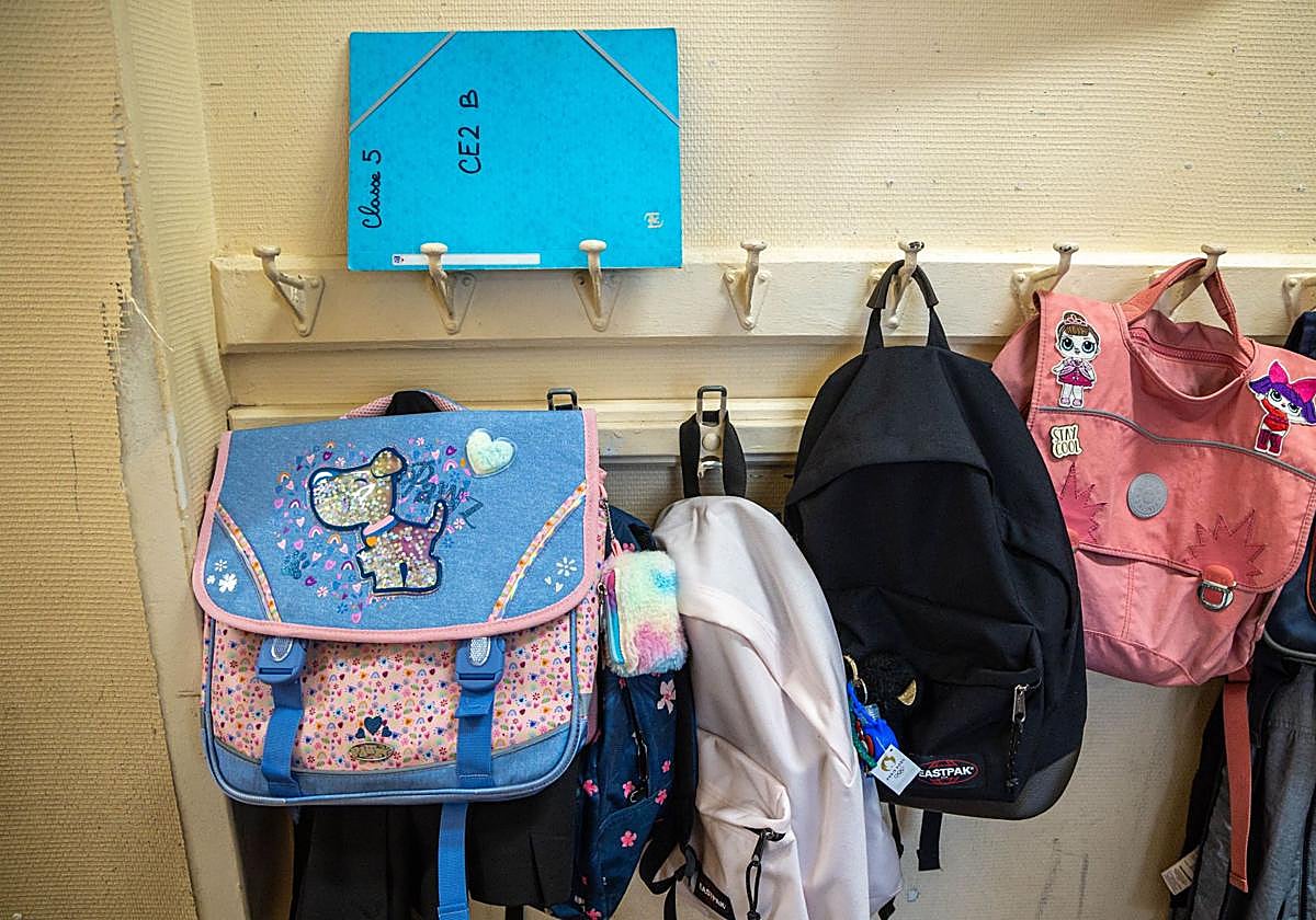 Mochilas colgadas de la pared de una escuela.