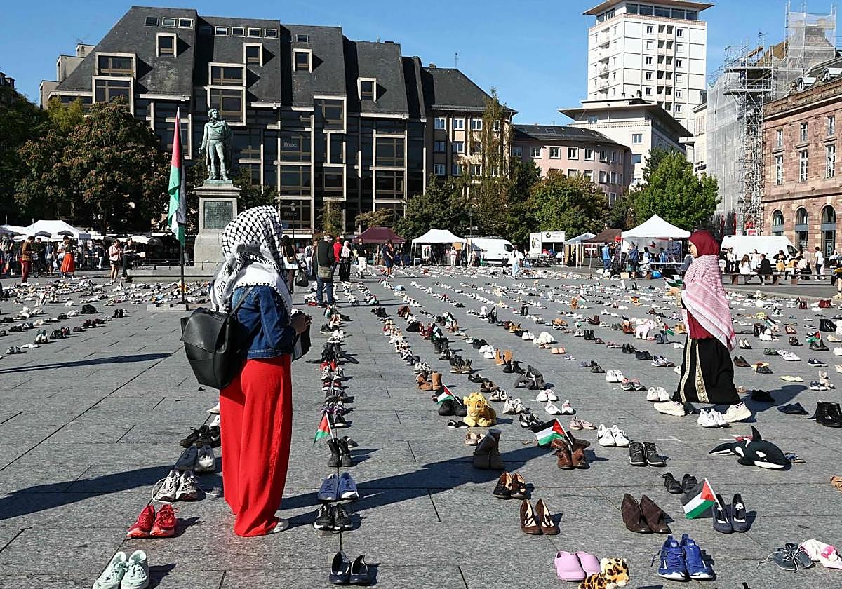 En Estrasburgo, mujeres entre zapatos colocados en la Plaza Kléber, símbolo de los palestinos muertos durante la ofensiva israelí en la Franja de Gaza, como parte de la acción simbólica «Operación Zapatos: ¡Vidas, no solo números!», del Colectivo Palestina 67.