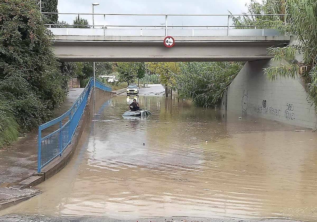 Una persona sobre un vehículo atrapado tras las fuertes lluvias en Cataluña.