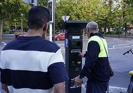 Un operario ayuda a un conductor a sacar el ticket.