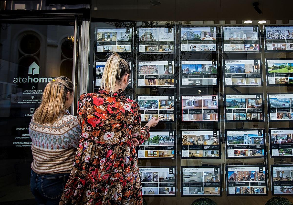Dos mujeres observan los anuncios de una inmobiliaria en Bilbao