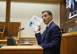 El lehendakari, Imanol Pradales, muestra el documento del Pacto de Salud en la tribuna.