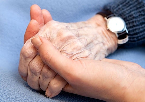 Una mano joven sostiene la mano de una persona mayor.
