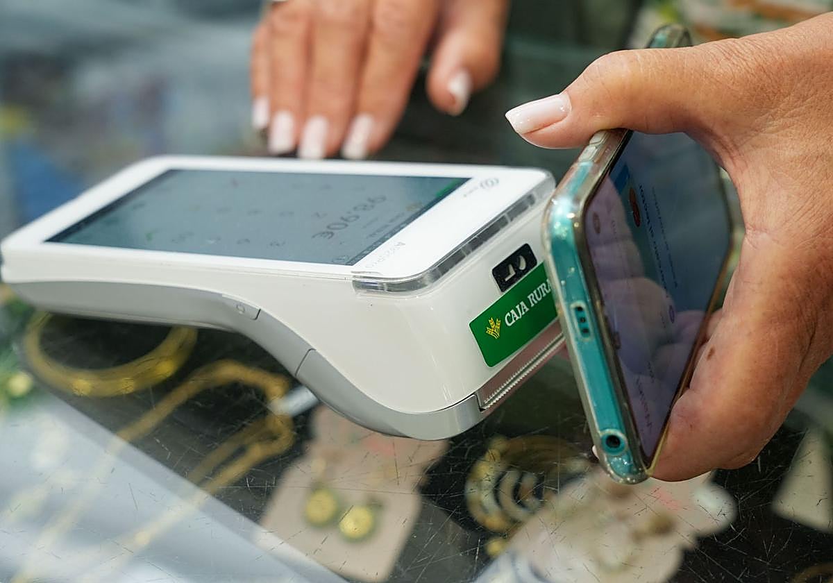 Una persona paga con su teléfono móvil en un comercio.