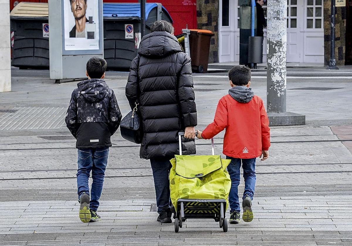 Una abuela acompaña a sus nietos al colegio.
