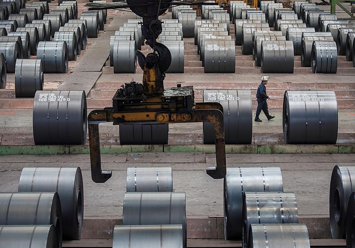 Un trabajador pasa junto a unos rollos de acero en una planta siderúrgica de China.