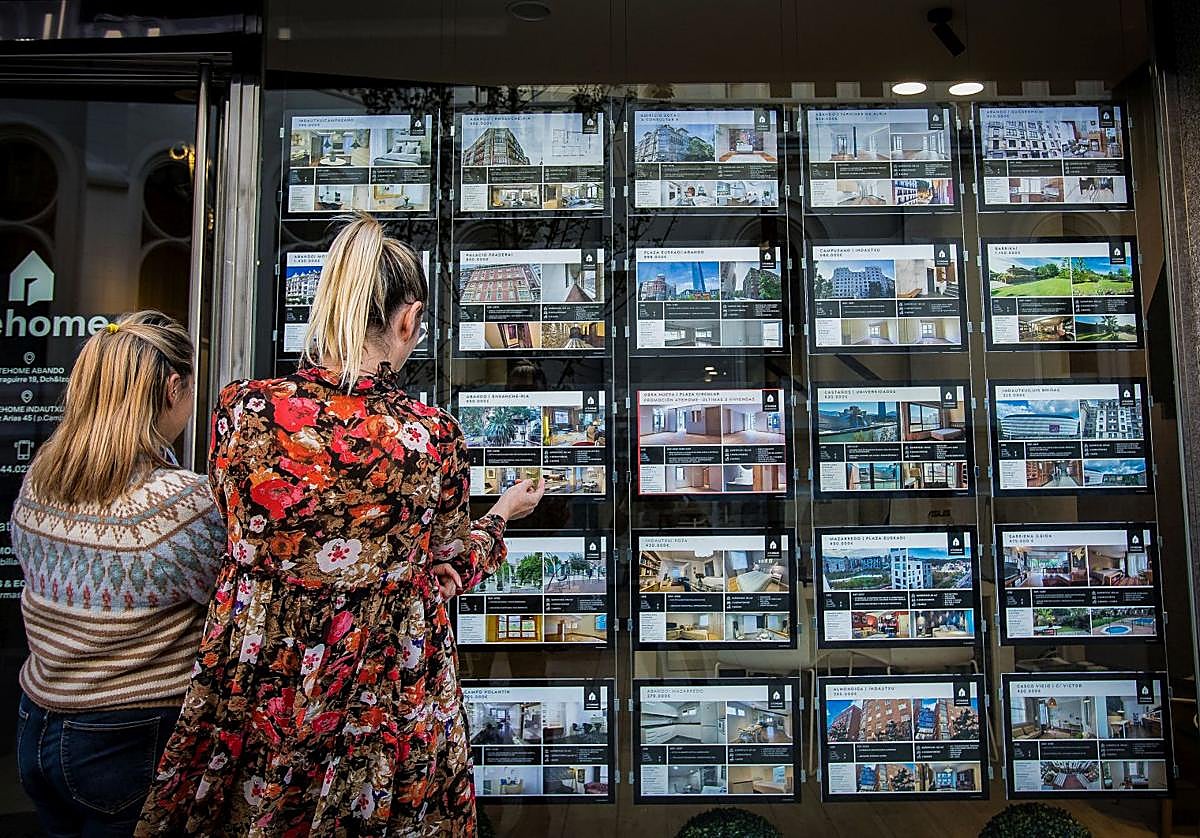 Dos mujeres observan el escaparate de una inmobiliaria.
