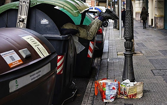 Una persona busca en un contenedor en Bilbao.
