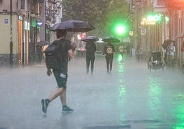 Un joven se cubre con un paraguas en Vitoria.