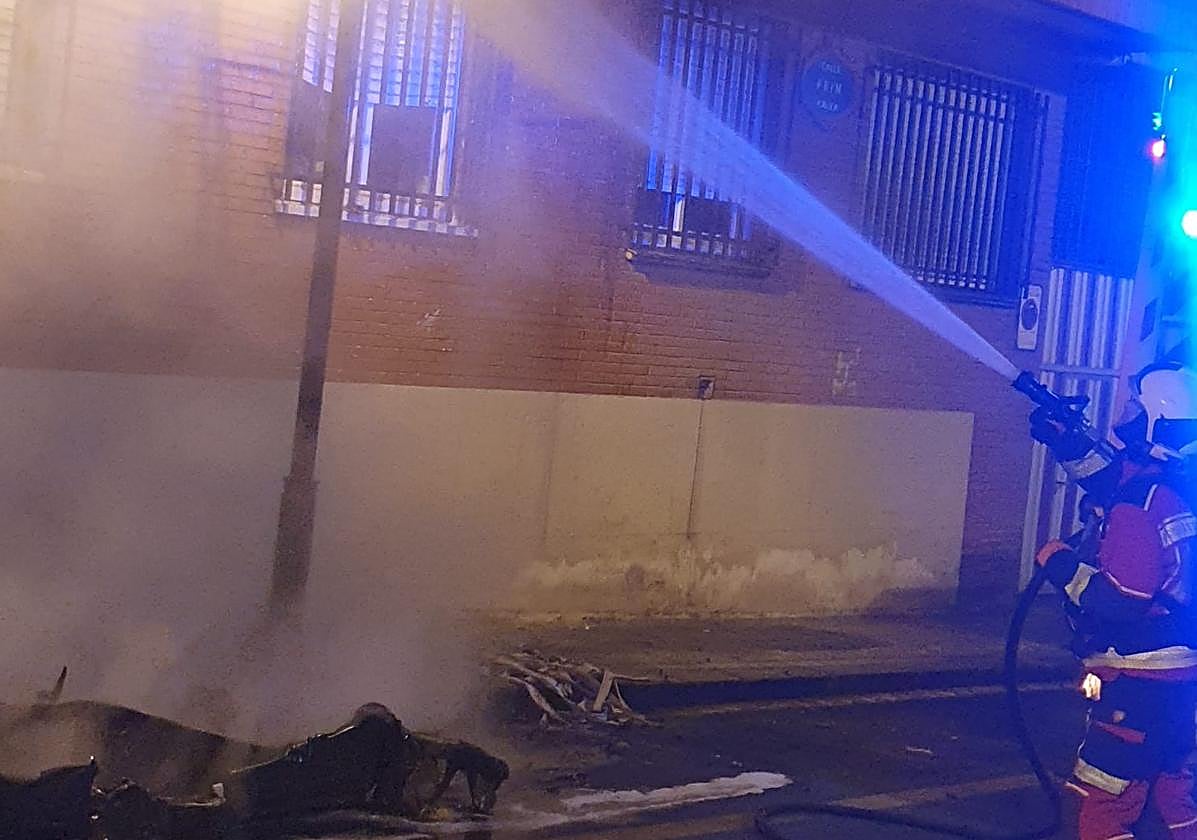 Un bombero apaga el incendio de un contenedor.