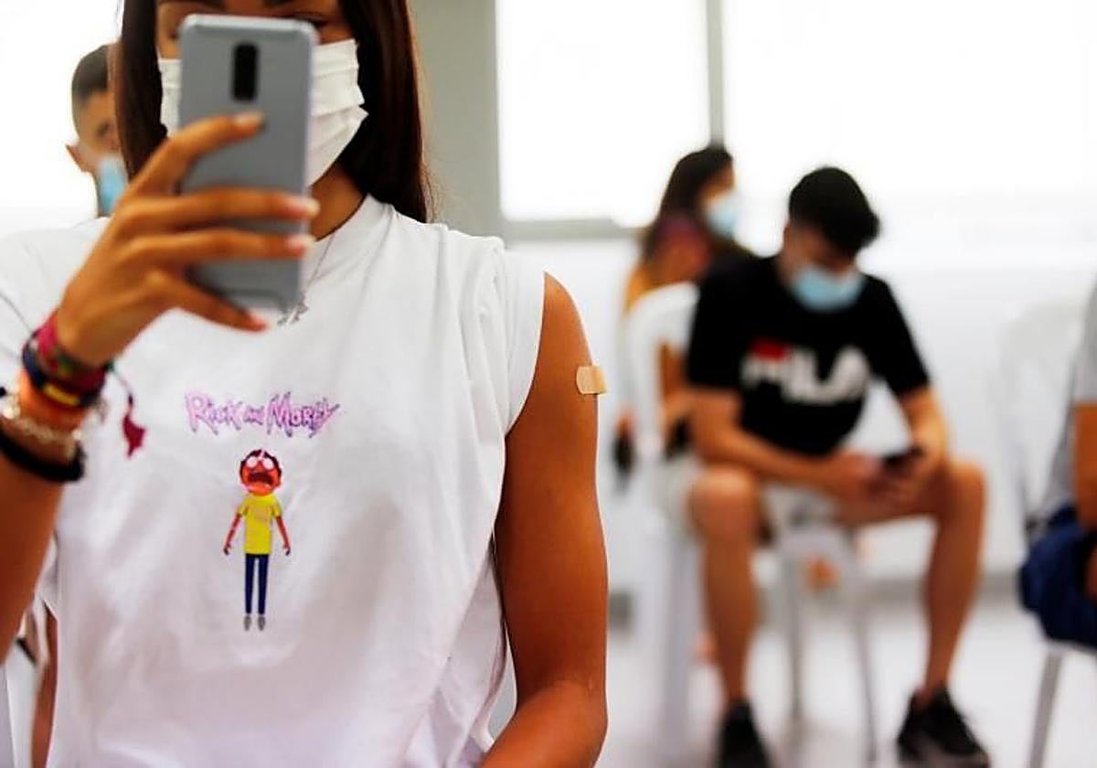 En la imagen una adolescente se hace una foto del brazo con la tirita tras recibir su primera dosis de la vacuna.