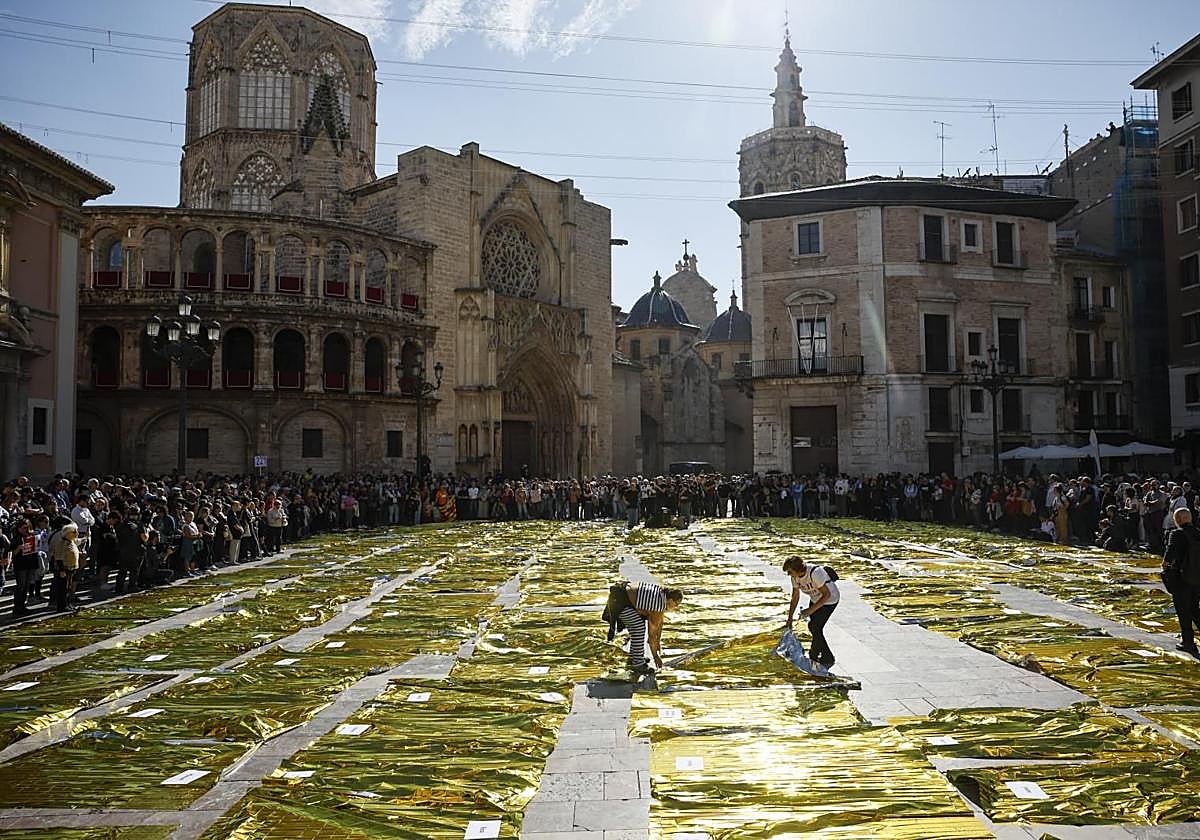 Doscientas veintinueve mantas térmicas han tapizado este miércoles el suelo de la zona central de la Plaza de la Virgen de València, en recuerdo de las 229 víctimas mortales de la dana.