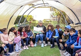 Alumnos de 2º de Primaria del colegio Vera Cruz atienden la lectura de una historia en inglés en el huerto del colegio.