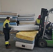 Un operario separa colchones en una planta de reciclaje