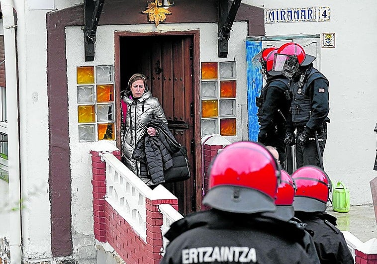 Naiara, una de las afectadas, saliendo de su casa el viernes, rodeada de ertzainas.