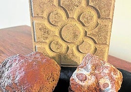 Un trozo de mineral Rojo Bilbao junto a una baldosa típica.