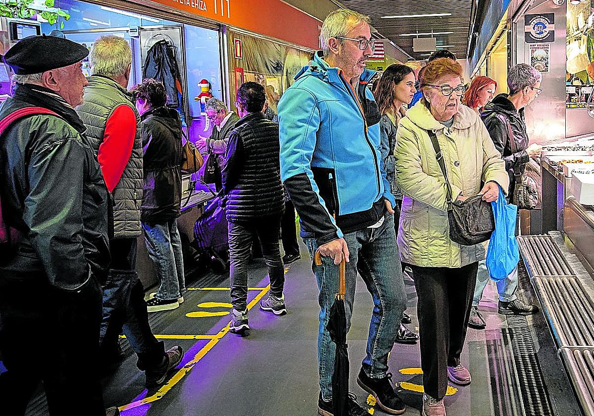 Clientes del Mercado de la Ribera ojean un puesto de pescadería.