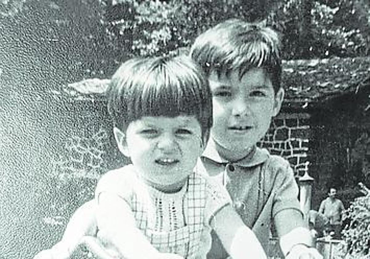 Dos niños, con un triciclo.