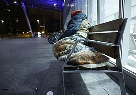 Una persona duerme en un banco de las calles de Vitoria.