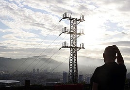 Una persona observa el cableado con el que red eléctrica transporta la energía sobre la ciudad de Bilbao