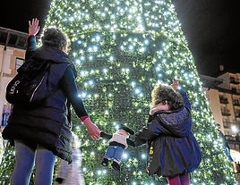 Una madre celebra con su hija el encendido del árbol de navidad instalado en Foru plaza de Gernika.