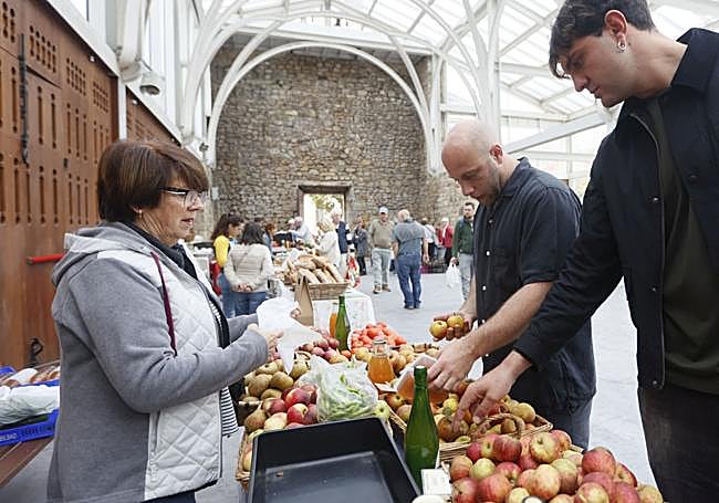 Cada semana Carlos y Jero se dejan caer por el mercado de Mungia. En la imagen, con Rosa, que les trae desde Gatika manzanas y sidra.