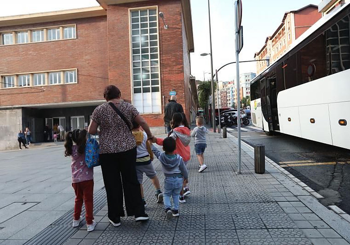 Una monitora acompaña a clase a alumnos de la escuela pública de Basurto tras bajarse del autobús.
