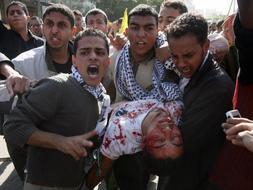 Un grupo de jóvenes traslada a un herido. / AFP