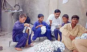 Varios menores, cosiendo balones de fútbol. / Archivo