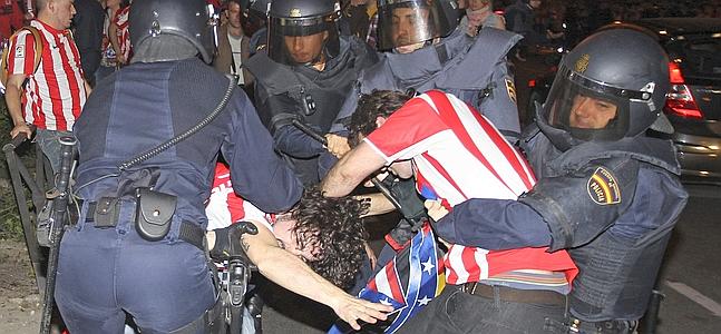 Miembros de la Policia intentan reducir a varios aficionados del Atlético de Madrid. / Víctor Lerena (Efe)