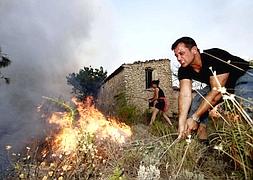 Un vecino trata de apagar el fuego. / Foto: Carlos Rodríguez | Vídeo: Atlas