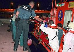 Oficiales de la Guardia Civil ayudan a desembarcar a los inmigrantes. / F.G. Guerrero (Efe)