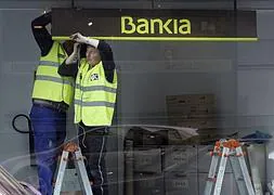 Dos trabajadores colocan un cartel de Bankia. / R. Pelaez (Reuters)