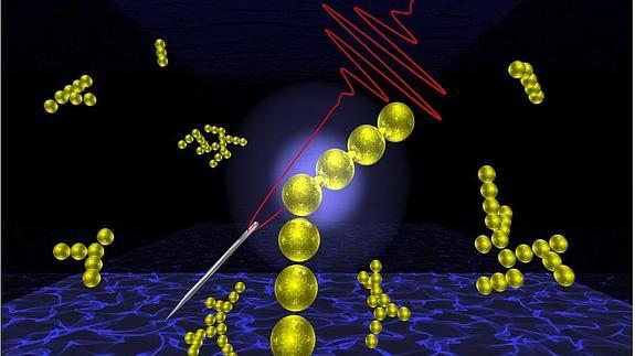 Representación del hilo láser enhebrando nanopartículas de oro. 