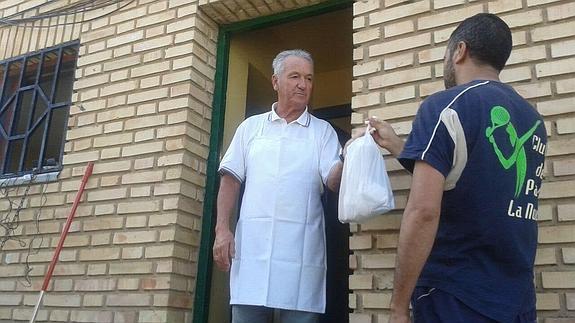 Un voluntario de Cáritas entrega bocadillos a un temporero. 