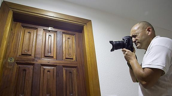 Un fotógrafo toma imágenes de la puerta de la vivienda donde se produjo el crimen. 