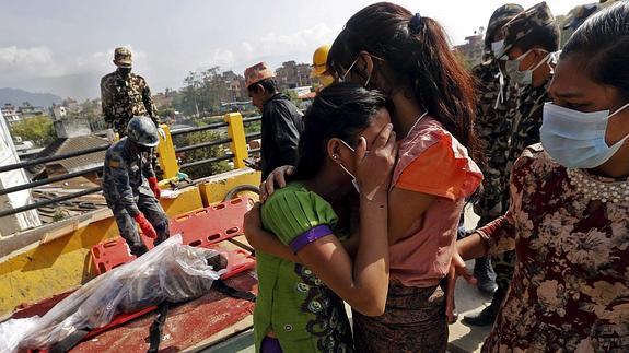 Dos mujeres lloran desconsoladas ante el cadáver de un familiar. 