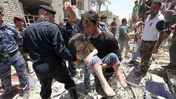 Un hombre lleva a un niño herido por la explosión. 