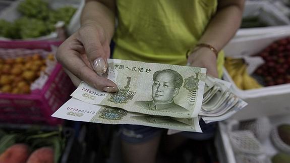 Una vendedora muestra billetes de yuan en Pekín. 