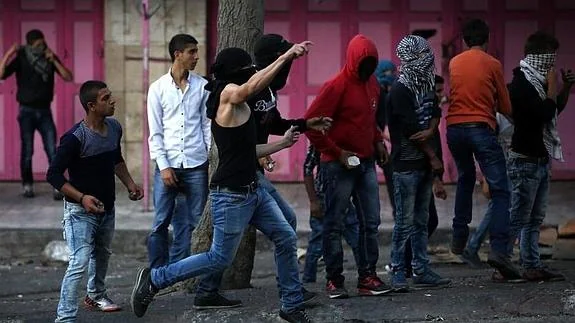 Jóvenes palestinos lanzan piedras a miembros de las fuerzas armadas israelíes en Hebrón. 
