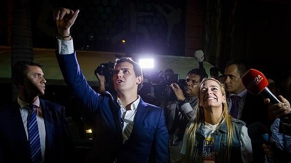 Albert Rivera (i) y Lilian Tintori (d) saludan al opositor encarcelado Daniel Ceballos a las afueras de su residencia.