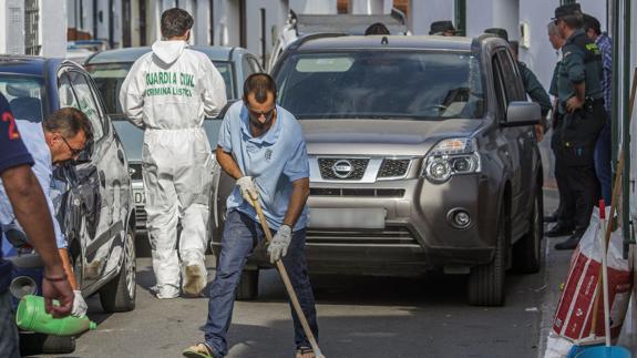 Operarios limpian la sangre de la puerta del domicilio.